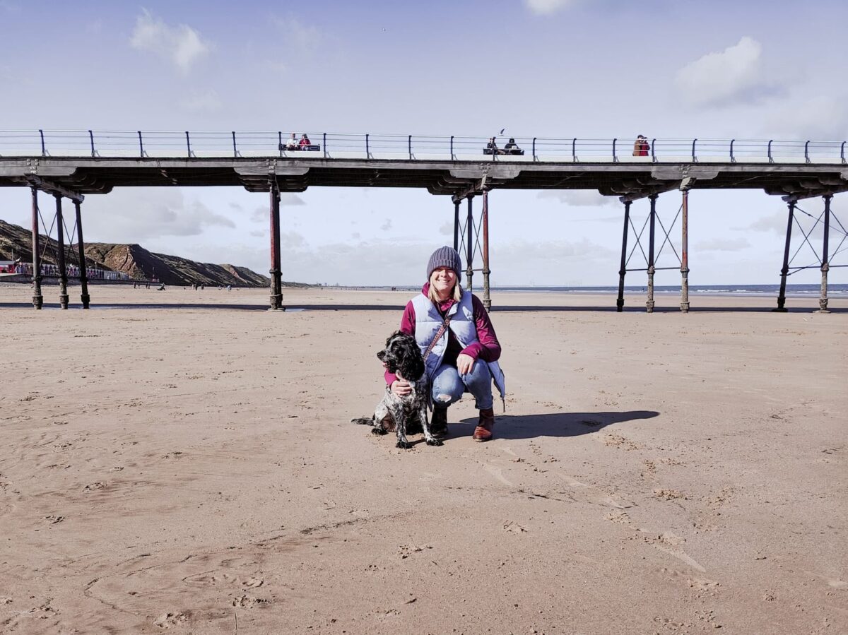 Lynn our roving reporters and her gorgeous spaniel on the Saltburn by the Sea shoreline with the pier visible