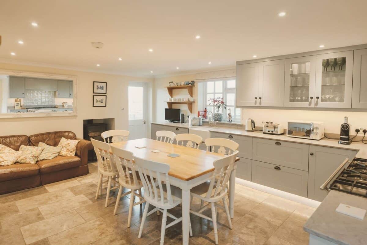 The spacious kitchen and dining area with a large table and sofa at Well Furlong Cottage, a luxury family retreat in the Cotswolds.