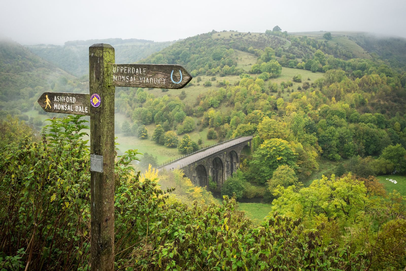 Dog friendly countryside view at Monsal Viaduct near Bakewell with a signpost pointing walking trails