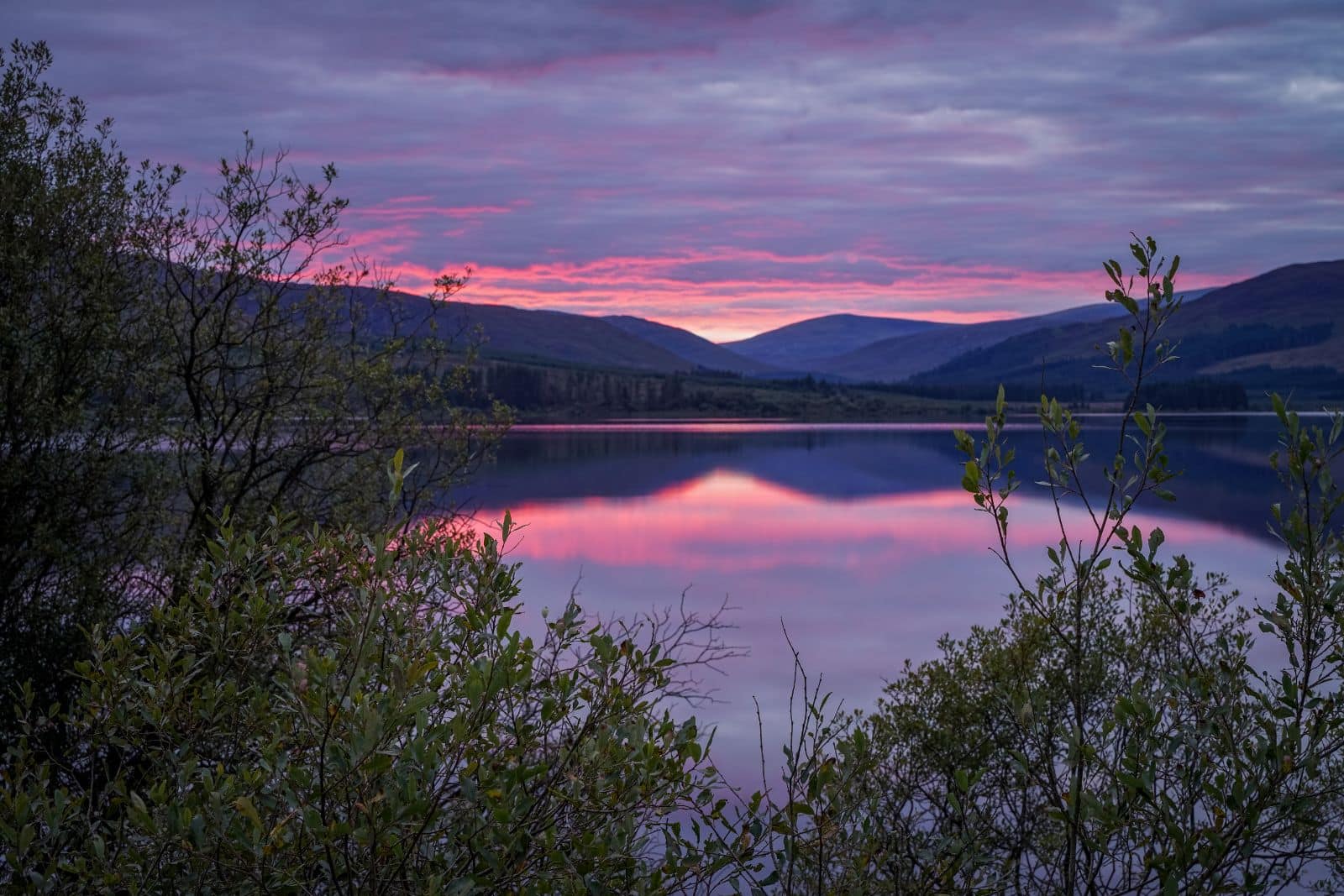 Lake and mountain view at sunset along the West Coast of Scotland with pink skies