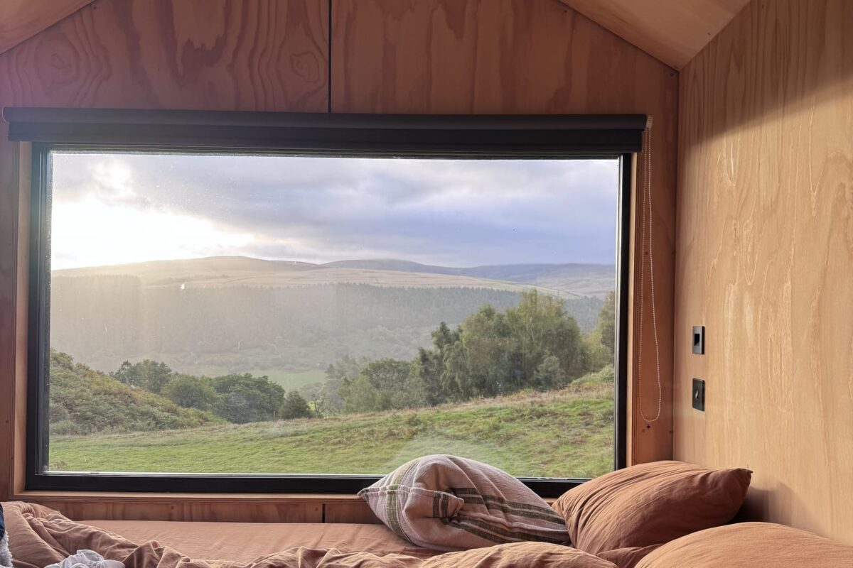 King size bed beneath the picture window framing the valley at Alula, Bala, North Wales