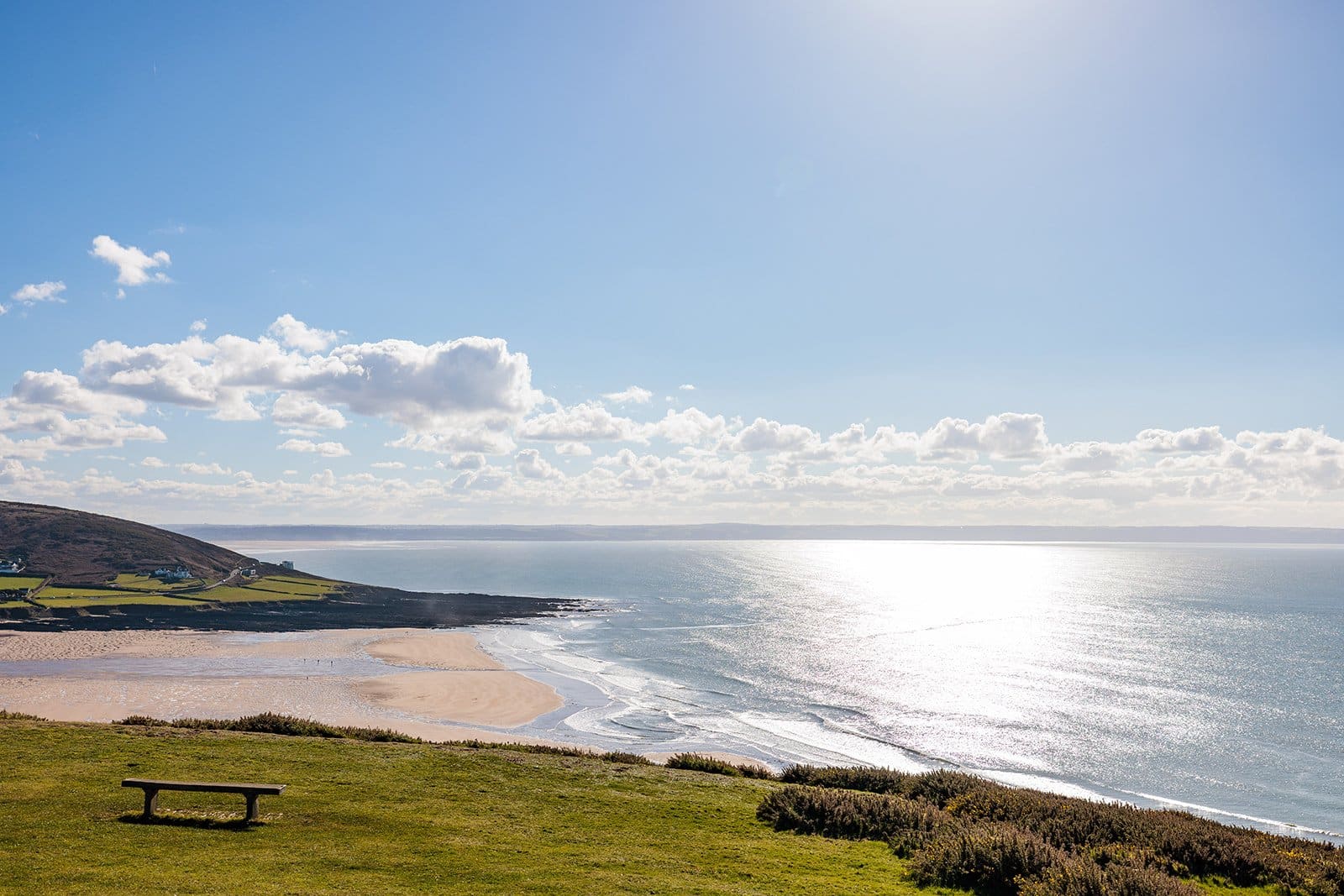 Bench overlooking Croyde Beach with sun sparkling on the sea, Croyde, North Devon