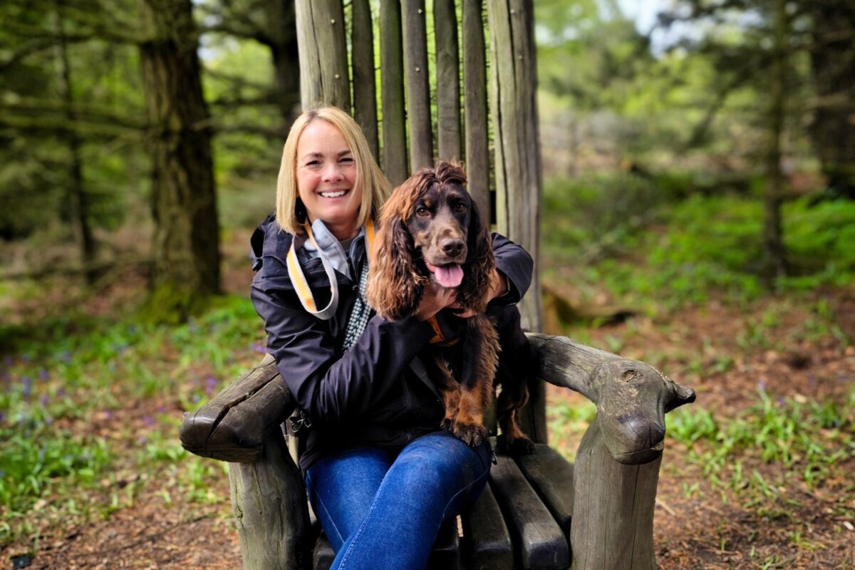 Cocker spaniel and owner resting on a carved wooden chair on the woodland trail at High Force, County Durham