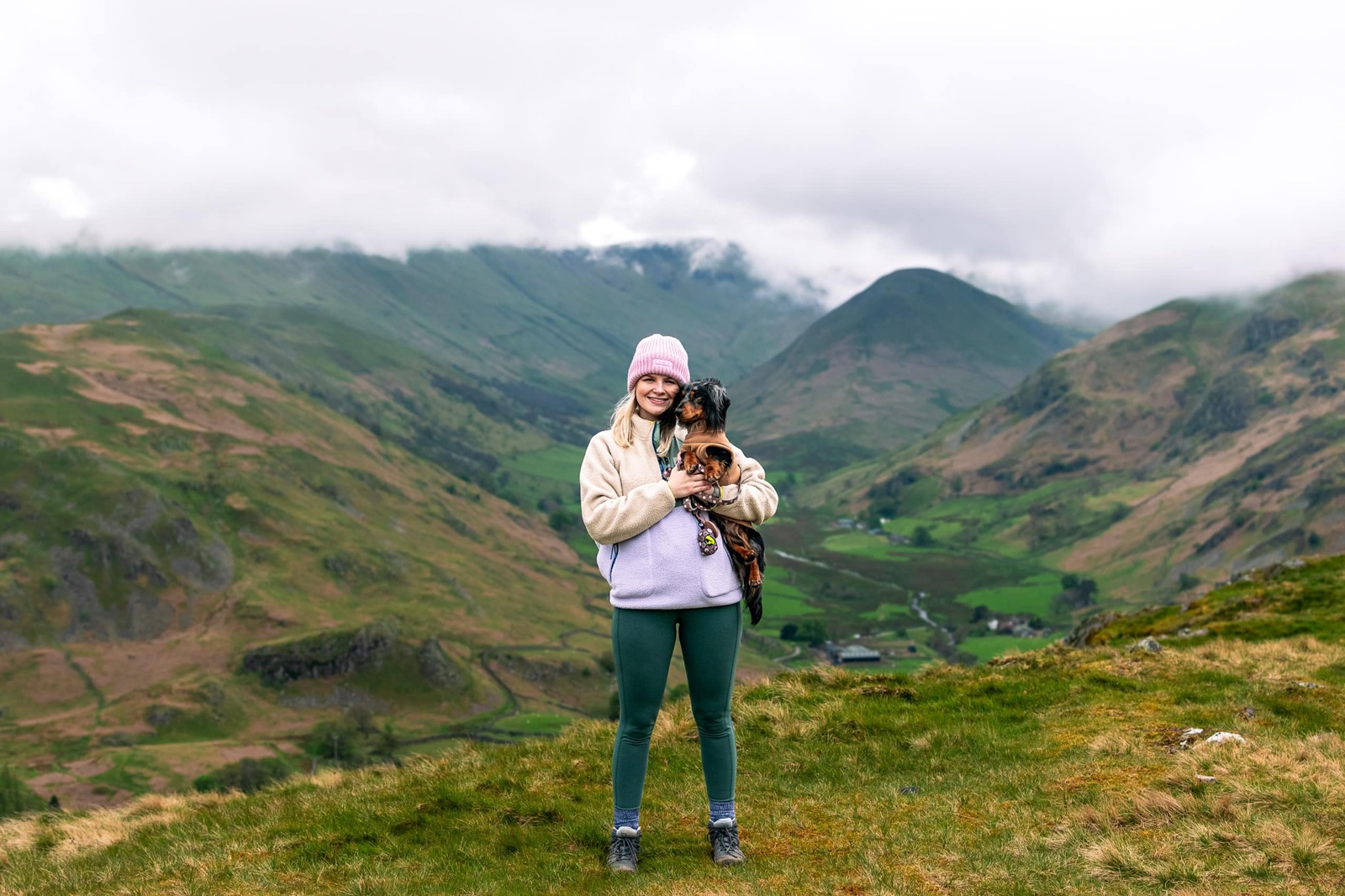 Lauren holding Ralph with panoramic mountain views at Hallin Fell in the Lake District
