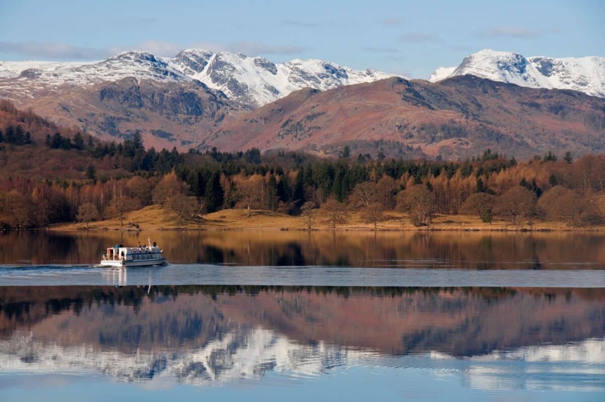Lake cruise on Windermere with snow-capped Langdale Pikes reflected in still water, Lake District